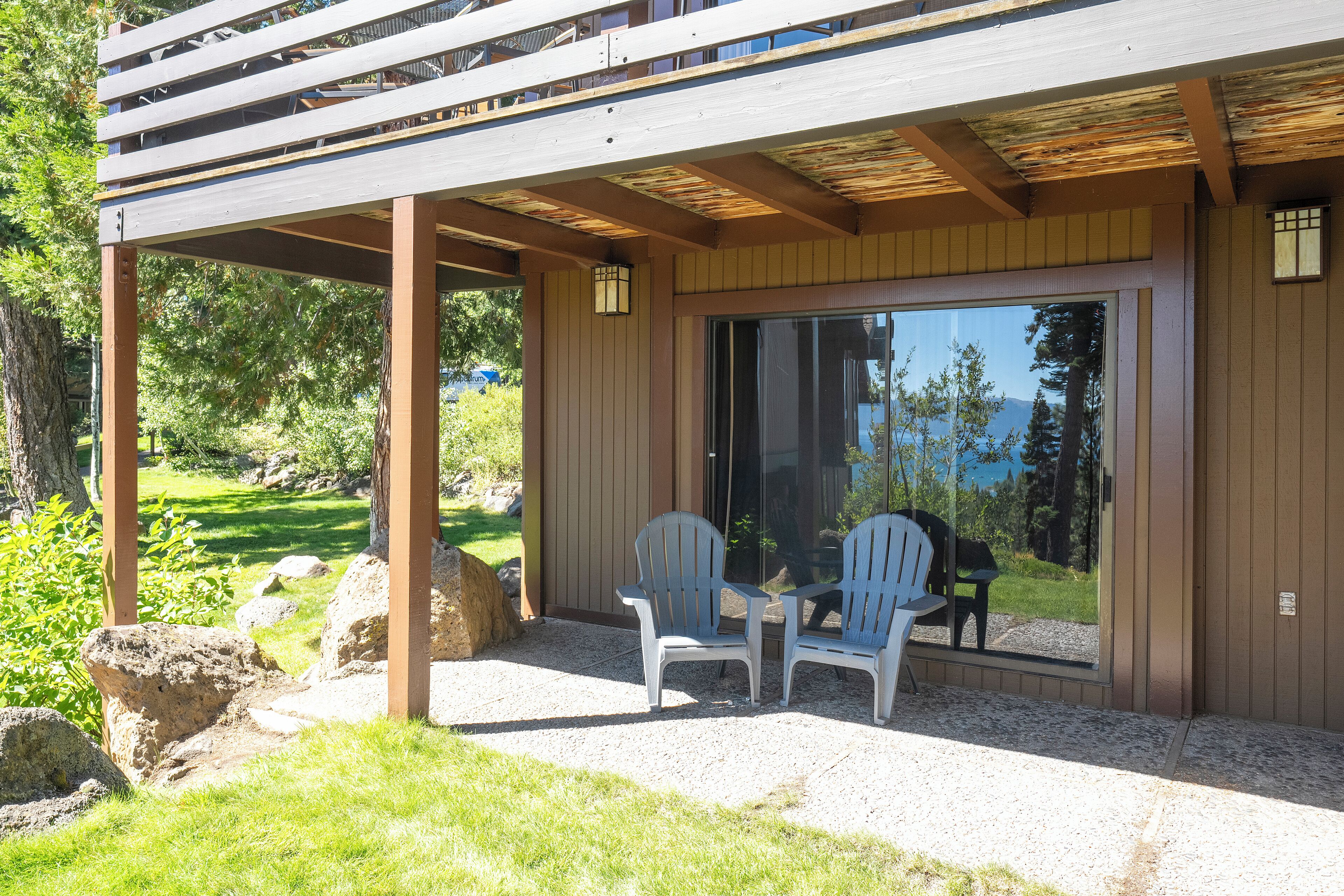 Un espacio al aire libre cubierto con dos sillas Adirondack, un pérgola de madera y vistas a una zona boscosa.