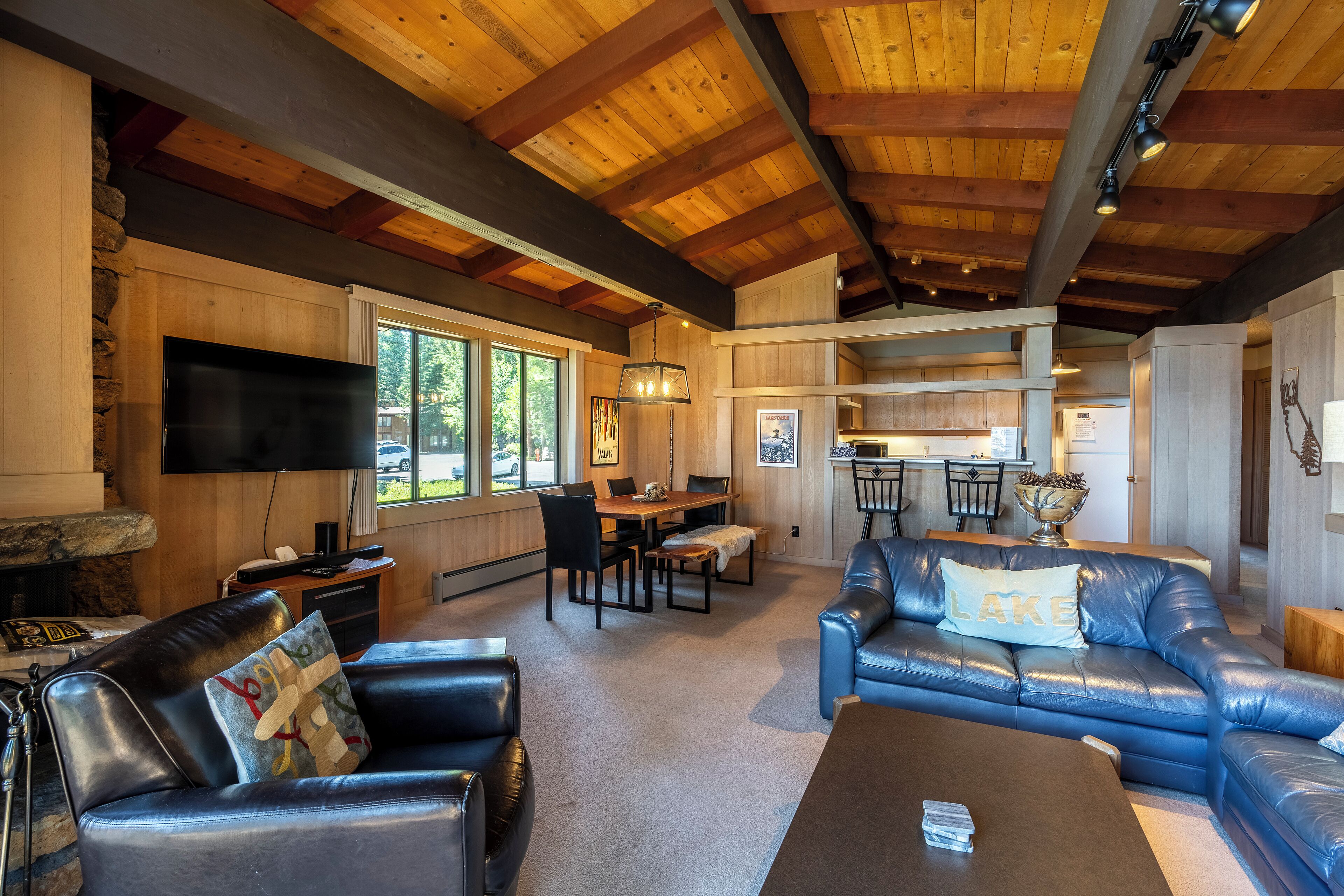 A spacious living area with a fireplace, leather sofas, a dining table, and a kitchen in the background.