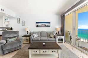 Ein Wohnzimmer mit einer Couch, Sesseln, einem Couchtisch und einem Bild eines Piers.