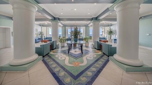 Eine geräumige Lobby mit einer zentralen Sitzgruppe, großen Säulen und einem gemusterten Boden.