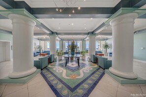 A spacious lobby with a central seating area, large columns, and a patterned floor.