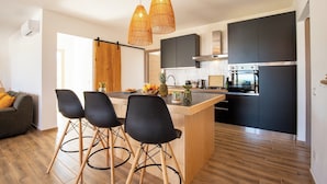 A modern kitchen with a central island, black cabinets, and a stainless steel refrigerator. - VILLA MAJU (Marina)