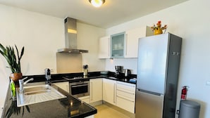 A modern kitchen with a stainless steel refrigerator, a built-in oven, and a gas stove. - Bluebay - TT#12: Poolside Ocean View - AIRCO  (Willemstad)