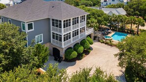 A two-story house with a balcony, a swimming pool, and a view of the ocean.