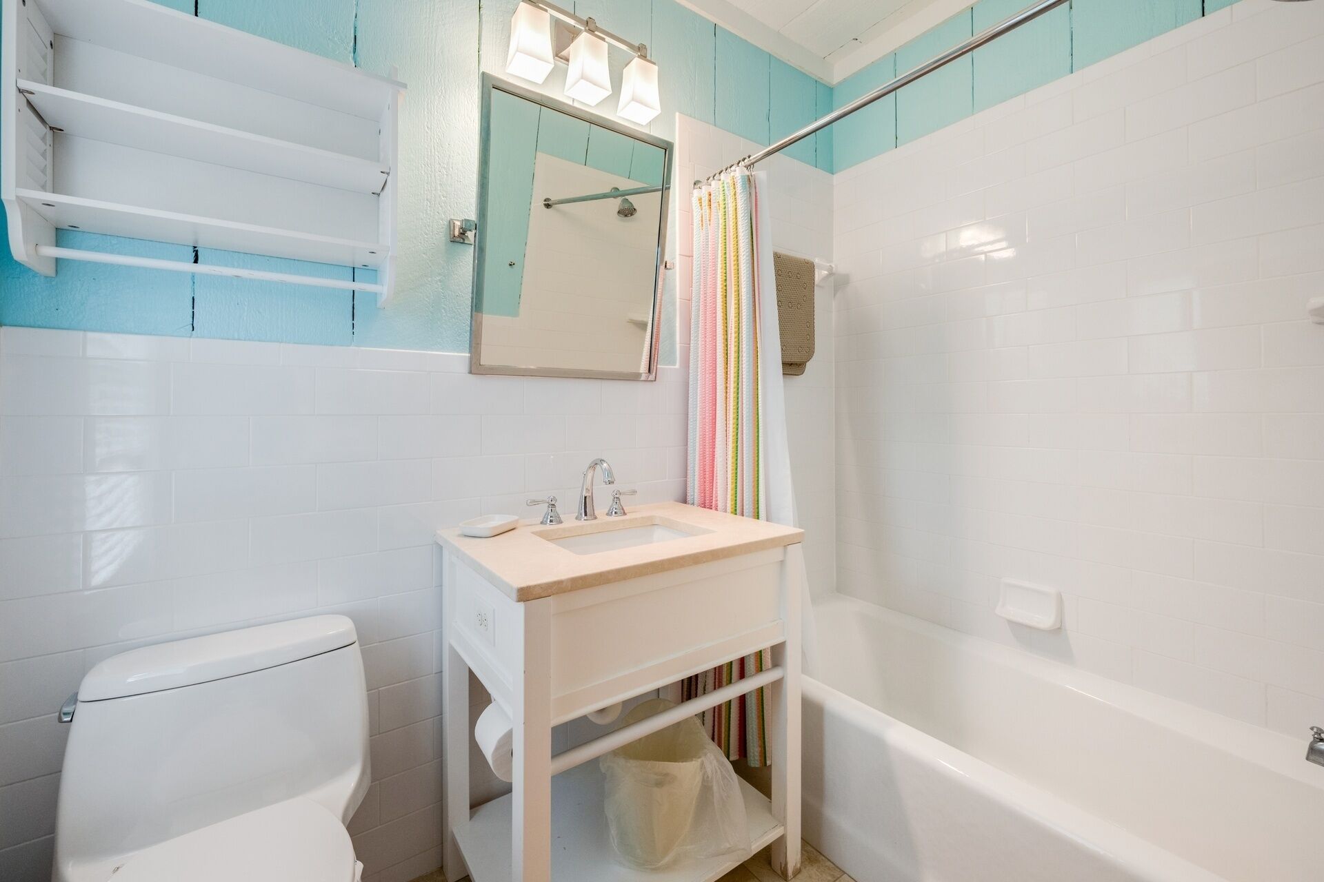 A bathroom with a toilet, sink, mirror, and shower.