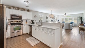 A kitchen with white cabinets, stainless steel appliances, and a central island. - Anchors Away In This Spacious And Beautiful Condo Overlooking Pond And 4th Hole 3 Bedroom Condo by Peace Vacations (Pawleys Island)