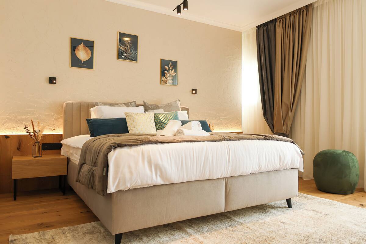 A bedroom with a bed, bedside tables, a bench, and artwork on the wall.