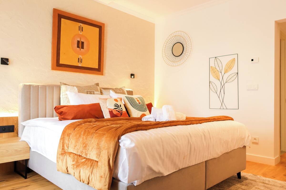 A modern bedroom with a large bed, a bedside table, and a nightstand.