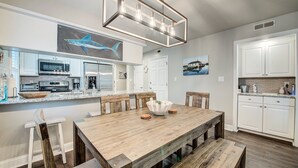 A modern kitchen with white cabinets, stainless steel appliances, and a wooden dining table with benches.