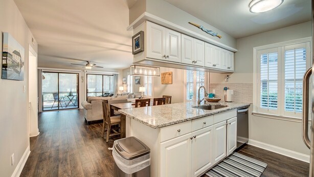 A modern kitchen with white cabinetry, a granite countertop, and a central island.