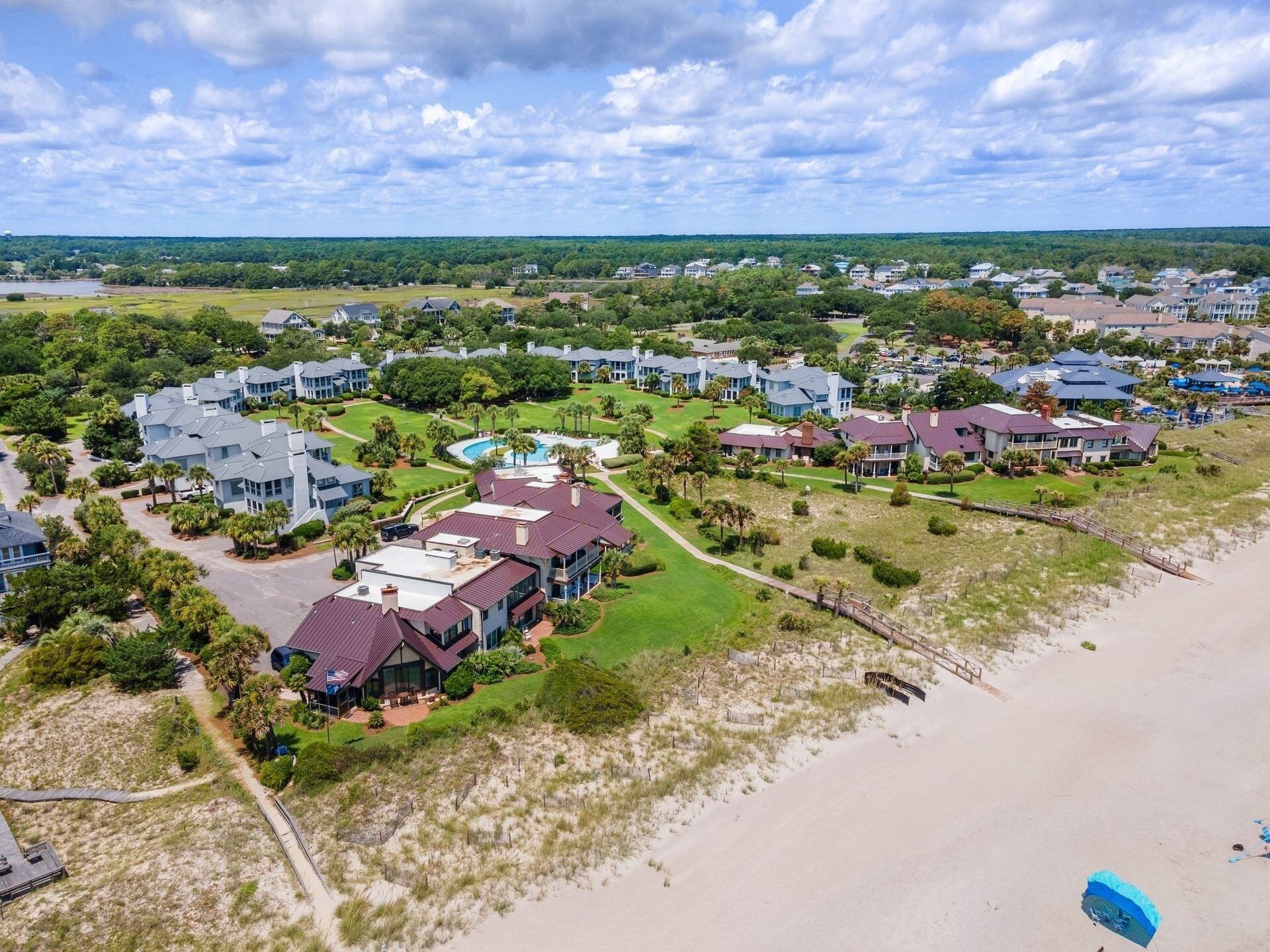 Vue aérienne d’une zone résidentielle côtière, avec des maisons, une plage et un terrain de golf.