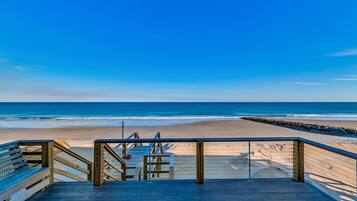 A wooden boardwalk leading to a beach with a clear view of the ocean.
