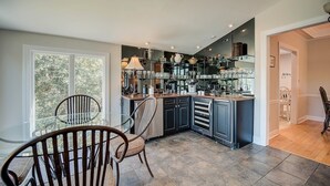 A modern kitchen with dark cabinetry, a central island, and a dining area with two chairs. - Looking For A Cozy Villa Located Next To The Golf Course? Good Trouble Is Your Answer! 3 Bedroom Villa by Peace Vacations (Georgetown)