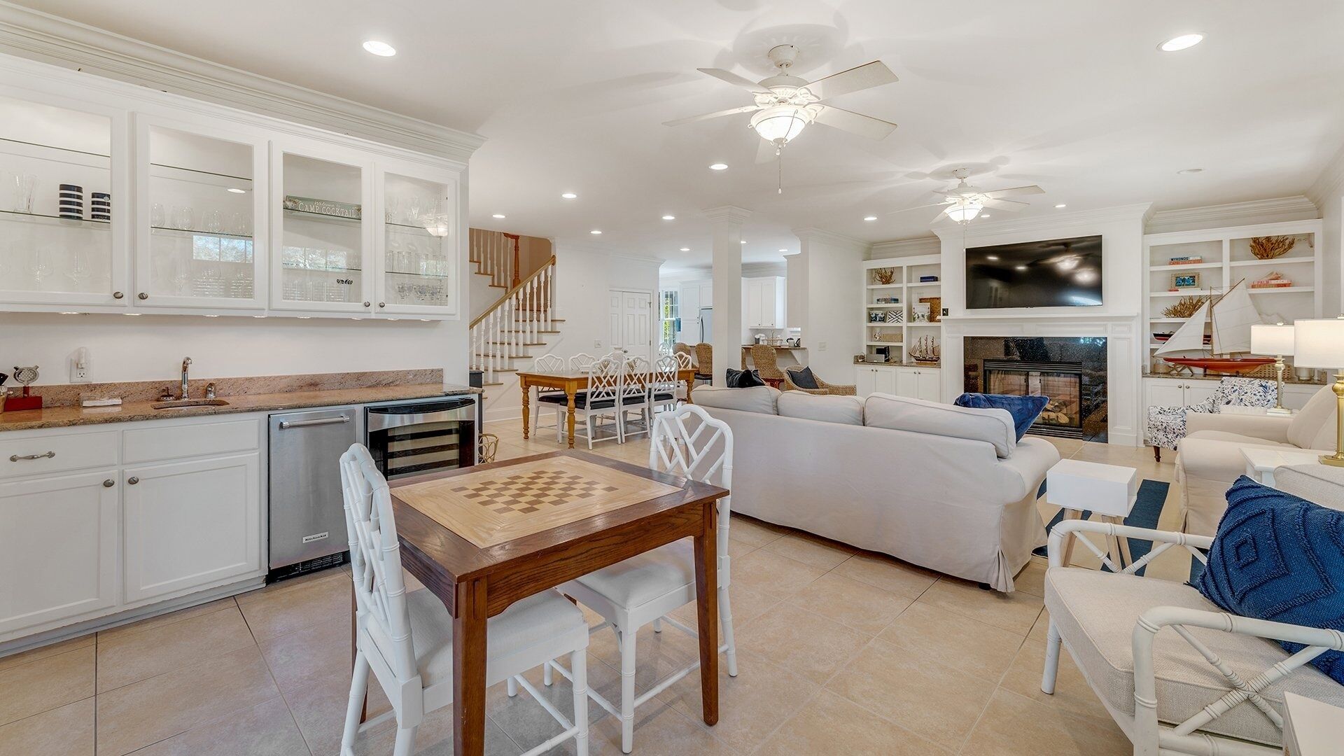 A spacious living area with a sofa, a dining table with chairs, a kitchen with white cabinets, and a fireplace.