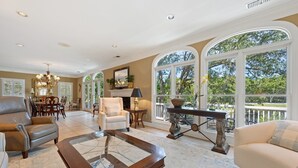 Un salón amplio con chimenea, asientos cómodos y ventanas grandes que ofrecen vistas al exterior.