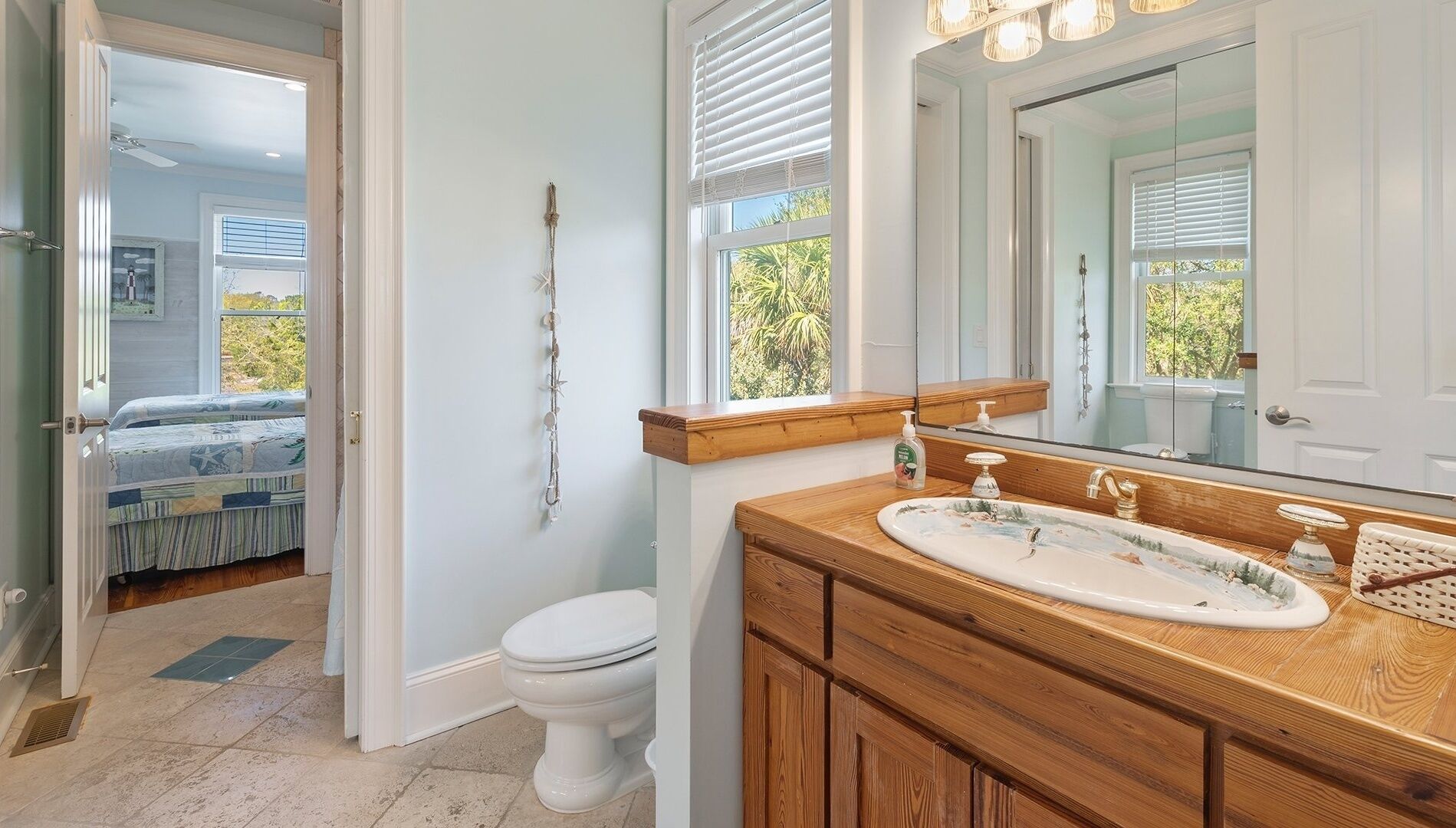 Une salle de bain avec un meuble-lavabo en bois, des toilettes blanches et un grand miroir.
