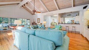 A spacious living room with a large blue sofa, wooden flooring, and a high ceiling with exposed beams. - Par Fore The Course Offers A Home Away From Home Feel. 4 Bedroom Home by Peace Vacations (Georgetown)
