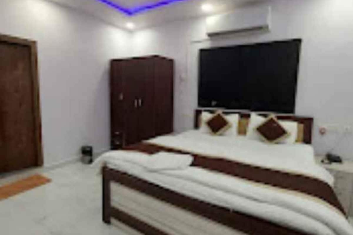 Une chambre à coucher comprenant un lit, une armoire, un téléviseur et un ventilateur de plafond.