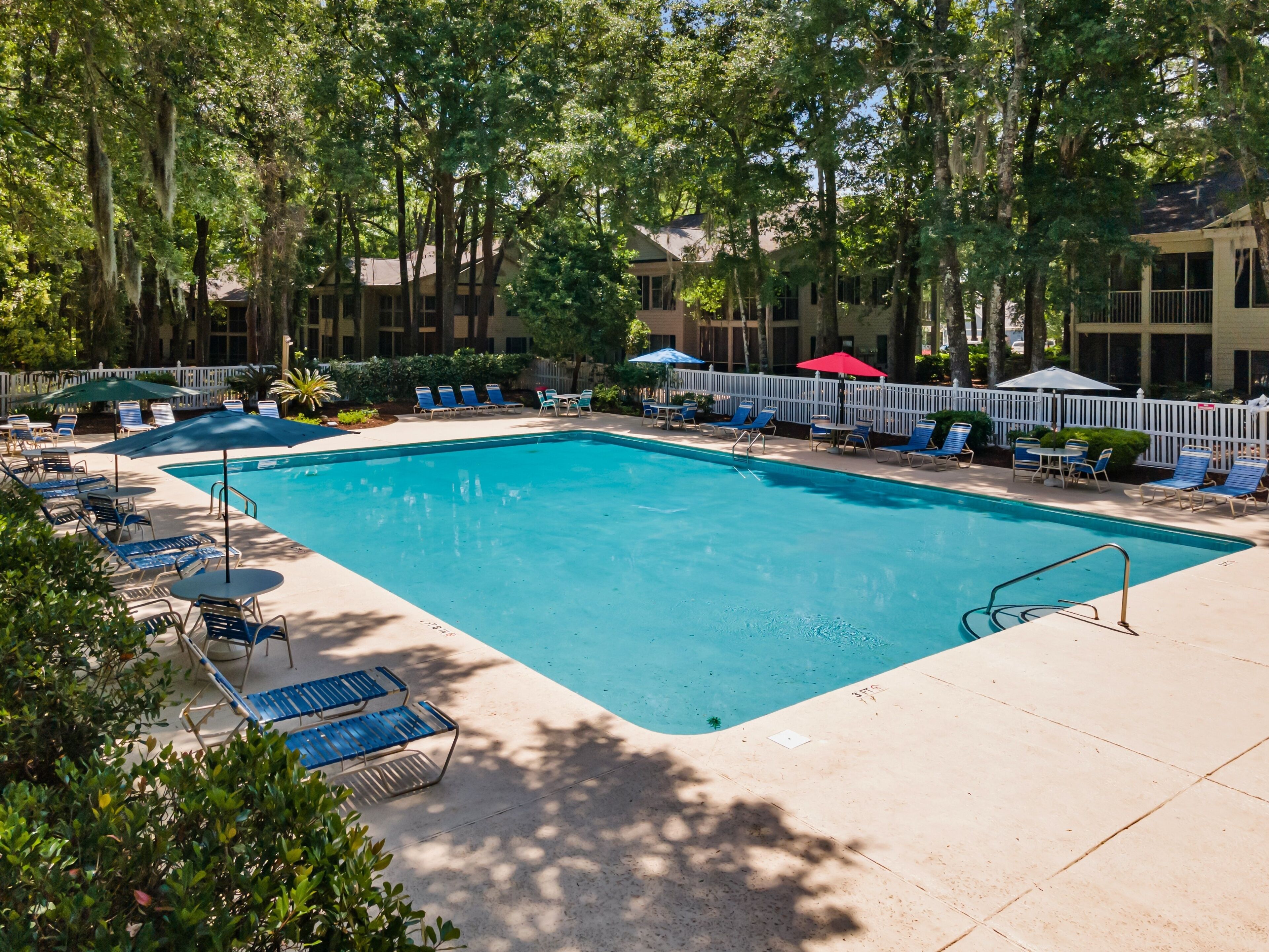 A rectangular swimming pool with blue water, surrounded by lounge chairs and umbrellas.