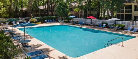 A rectangular swimming pool with blue water, surrounded by lounge chairs and umbrellas.