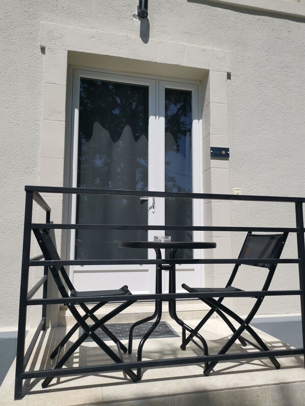 Un balcon avec une balustrade en métal, une table et deux chaises.