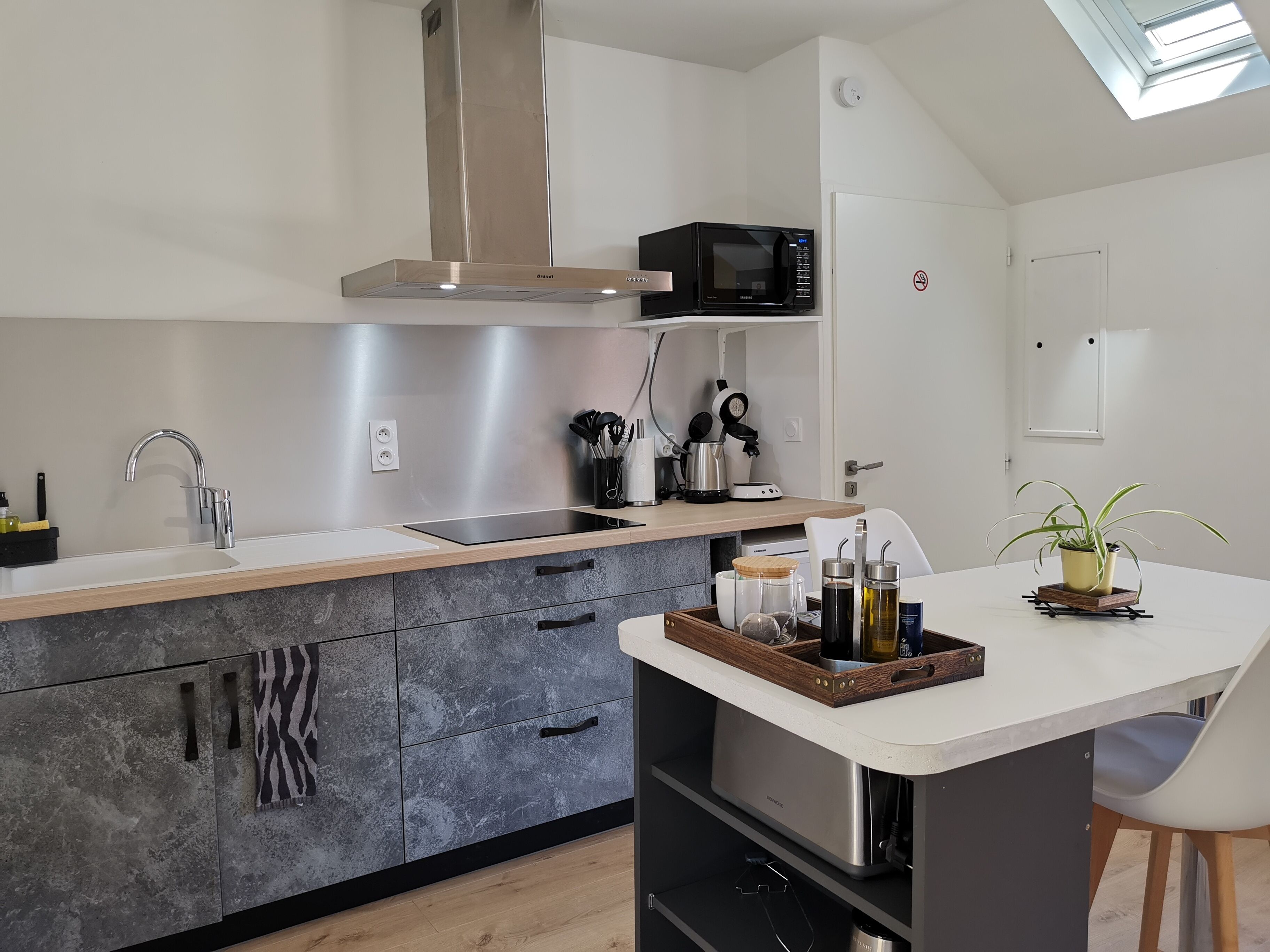 Una cocina moderna con campana extractora de acero inoxidable, microondas y cafetera sobre la encimera.