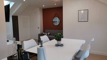 A modern dining area with a white table, chairs, and a central plant.