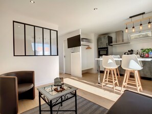 Een moderne keuken met witte kasten, een inbouwoven en een eethoek met witte stoelen en een glazen tafel.