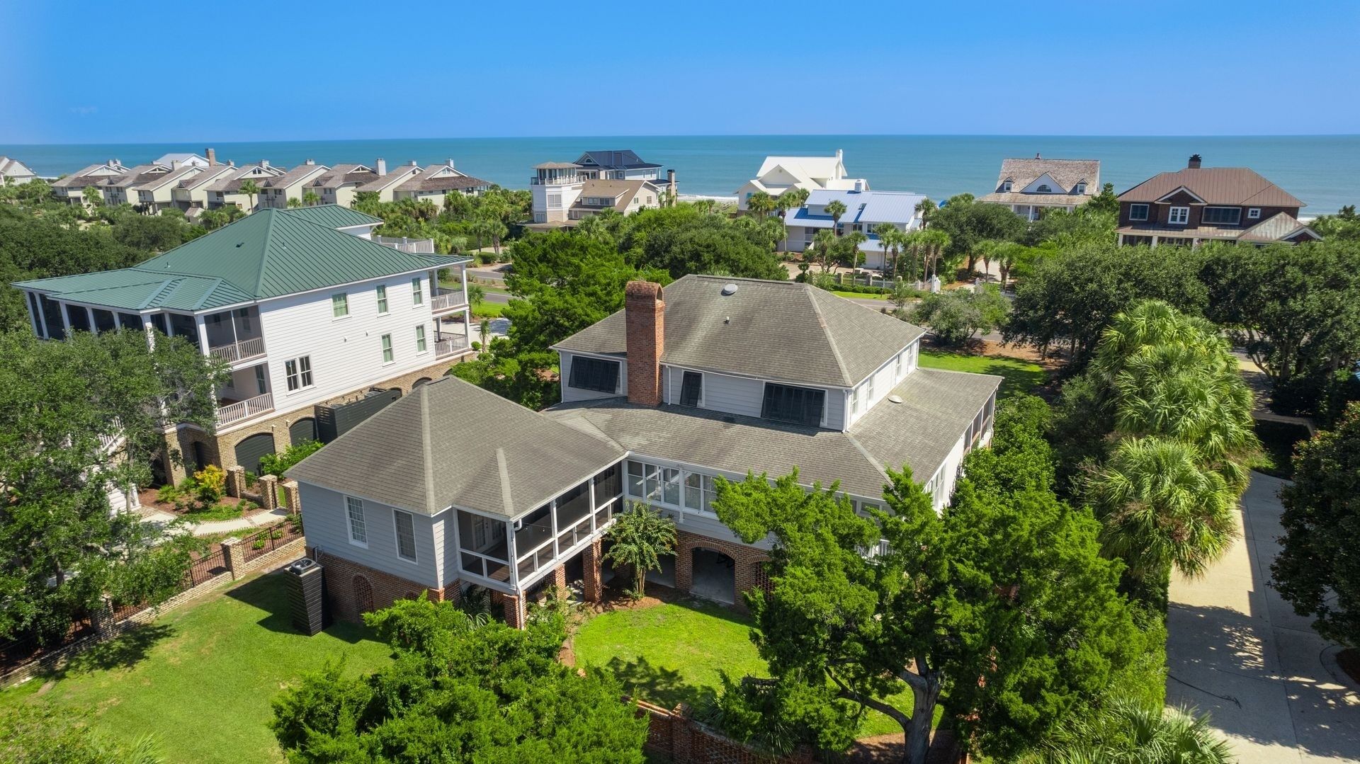A residential area with houses, a large lawn, and a view of the ocean.