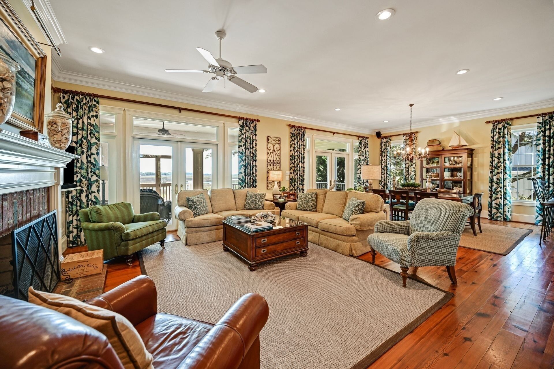 A spacious living room with a fireplace, a ceiling fan, and a dining area with a chandelier.