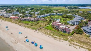 Une station balnéaire avec des chalets situés en bord de mer, une piscine et, en arrière-plan, un terrain de golf.