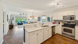 A modern kitchen with white cabinetry, stainless steel appliances, and a central island.