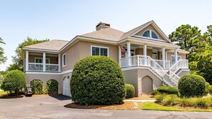 Stunning two-story home with a central entrance, covered porch, and beautifully manicured grounds.