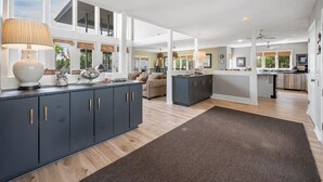 A spacious kitchen with a central island, dark cabinetry, and a large window providing natural light.