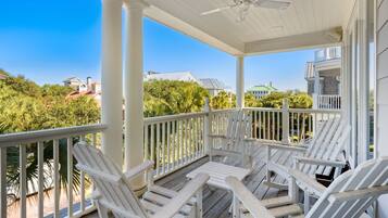 Une véranda couverte avec des balustrades en bois peintes en blanc et des fauteuils Adirondack.