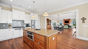 A spacious kitchen with white cabinetry, a granite countertop, and a central island.