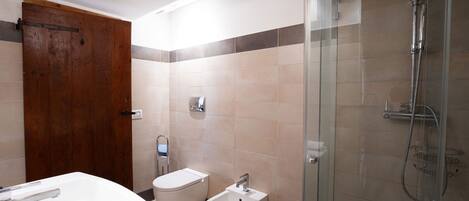 A bathroom with a shower, toilet, bidet, and sink.
