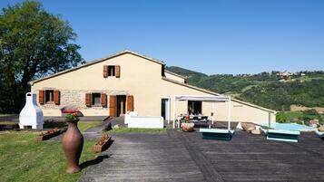 A house with a stone facade, wooden shutters, and a patio with outdoor furniture.