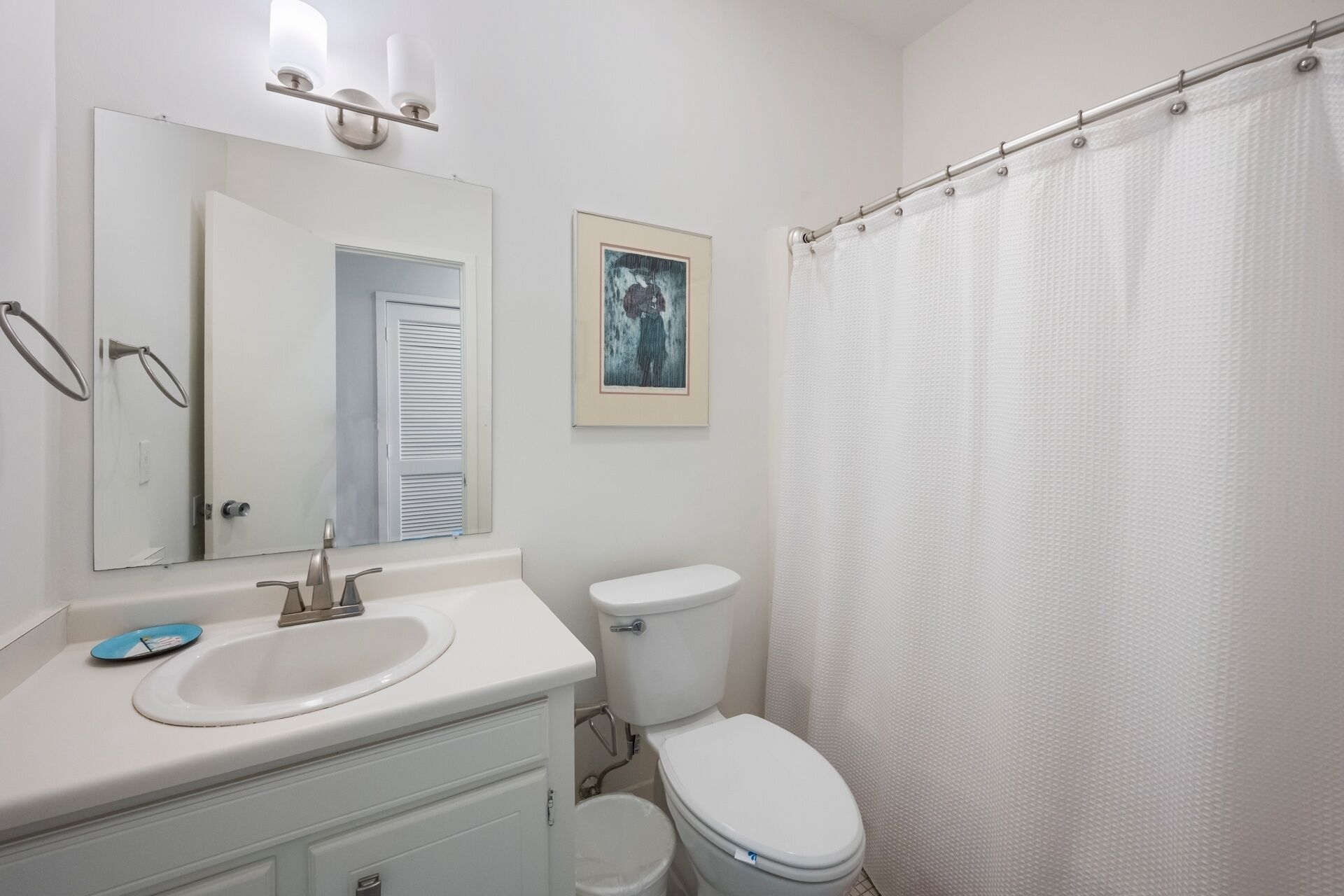 A bathroom with a sink, toilet, and shower curtain.