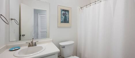 A bathroom with a sink, toilet, and shower curtain.