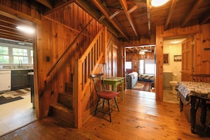 A wooden interior with a staircase, a dining table, and a kitchen area. - Traditional Waterfront Maine Cottage on Long Lake with great swimming. (Naples)
