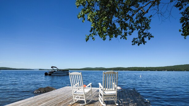 A wooden dock with two rocking chairs facing a calm lake. - Traditional Waterfront Maine Cottage on Long Lake with great swimming. (Naples)