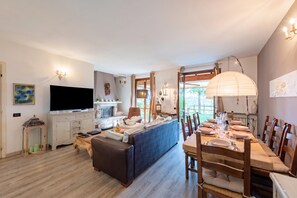 A modern living room with a TV, sofa, and dining area with chairs and a table. - Homesweethome Lake-view Villetta a Schiera With Garden (Besozzo)