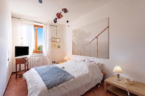 A bedroom with a bed, a TV, a lamp, and a painting on the wall. - Homesweethome Lake-view Villetta a Schiera With Garden (Besozzo)