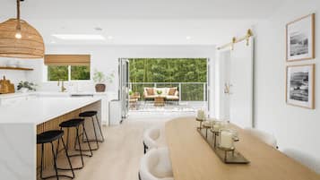 A modern kitchen with a large island, bar stools, and a dining area with a wooden table and candles.