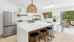 Una cocina moderna con una isla grande, electrodomésticos de acero inoxidable y una lámpara colgante.