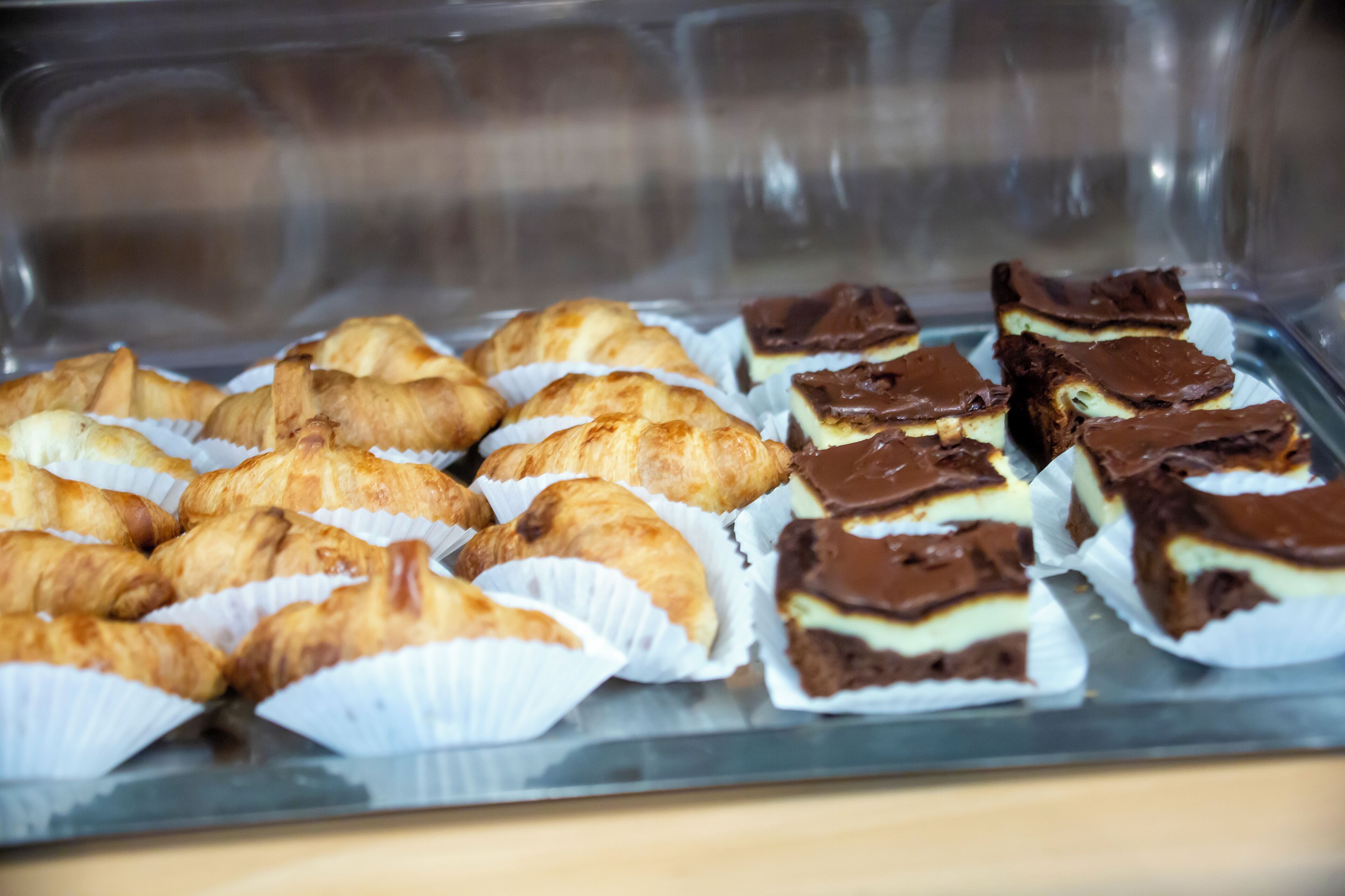 Une variété de pâtisseries, notamment des croissants et des carrés au chocolat, présentées sur un plateau.