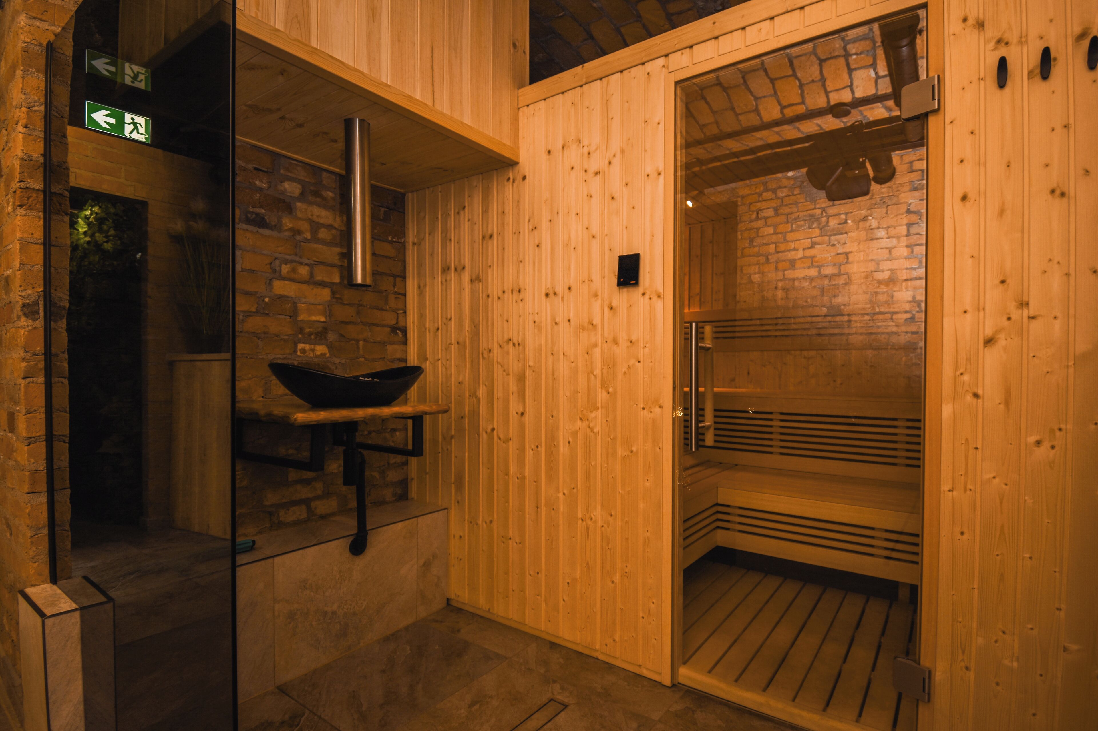 A wooden sauna with a black sink and a bench.