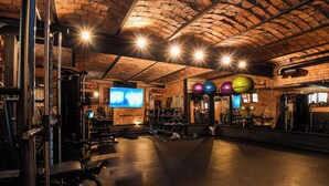 Een sportschool met bakstenen muren, trainingsapparatuur en een digitale klok die 15:34 aangeeft.