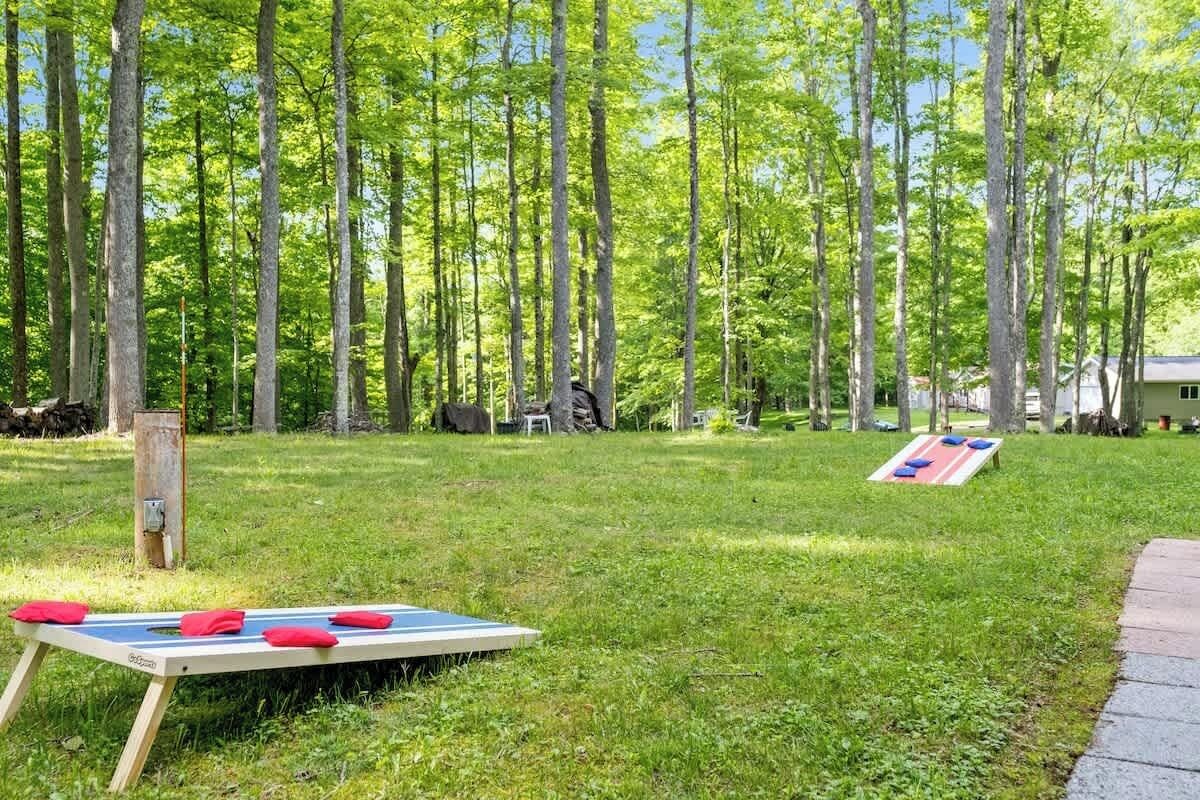 An outdoor area with a grassy field, a wooden structure, and a small building in the background.